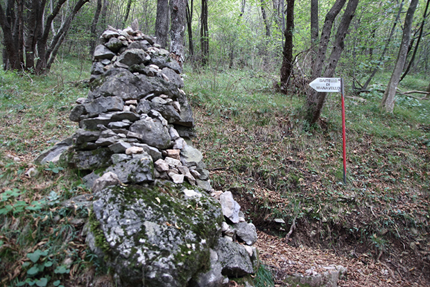 Ometto in pietra con il cartello che indica il Bivacco Baitello di Manavello